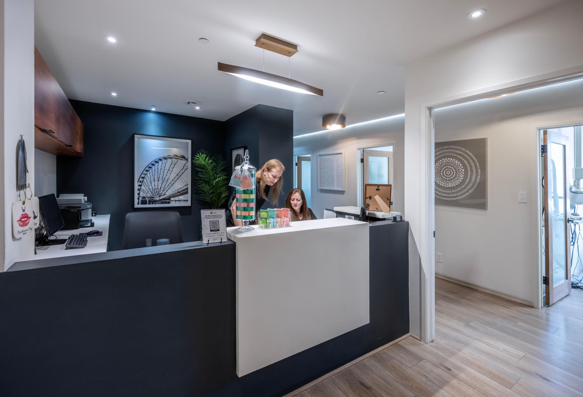 Two employees at a reception desk in an outpatient medical office.