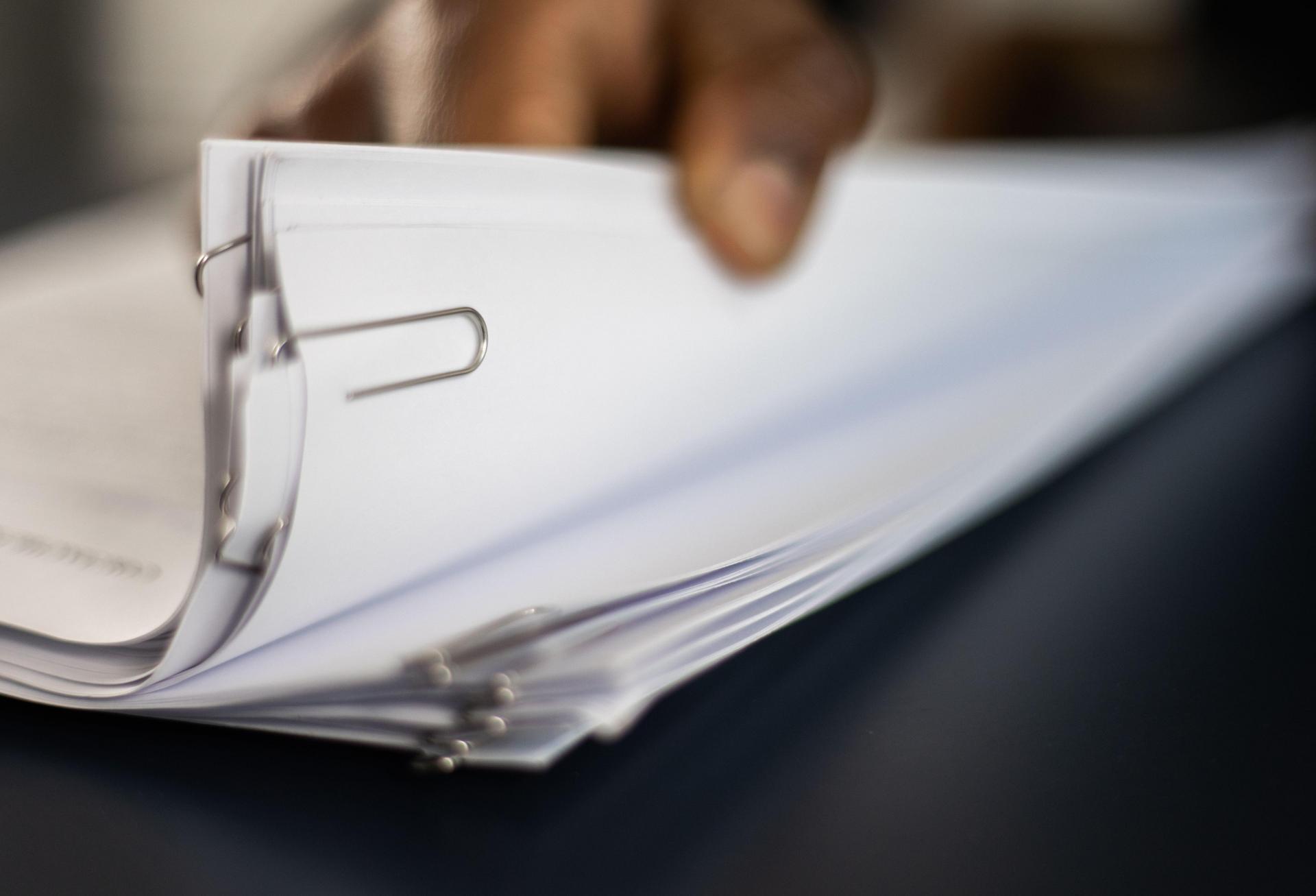 A person thumbing through a stack of paperwork.