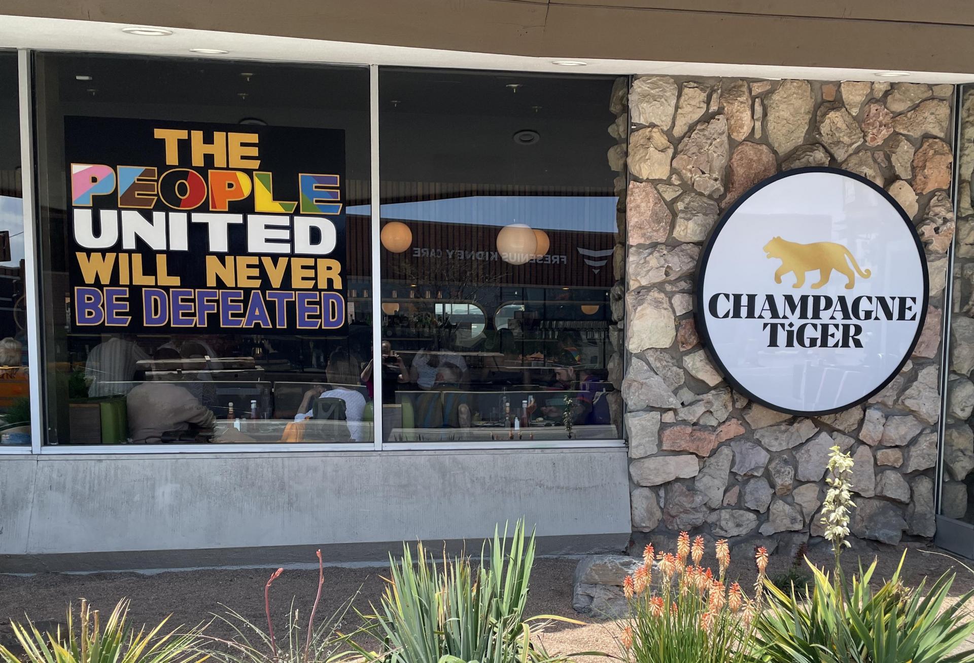 A photo of the storefront at Champagne Tiger, with a sign in the window that reads 
