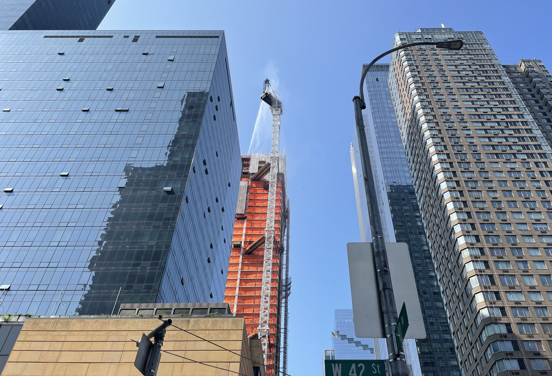 Firefighters spray a collapsed crane on 10th Avenue in Manhattan after a fire led it to collapse and hit a neighboring building.