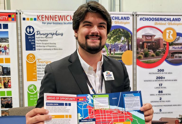 Kennewick Economic Development Manager Miles Thomas holds up a map of the city's opportunity zones at ICSC RECon 2019.