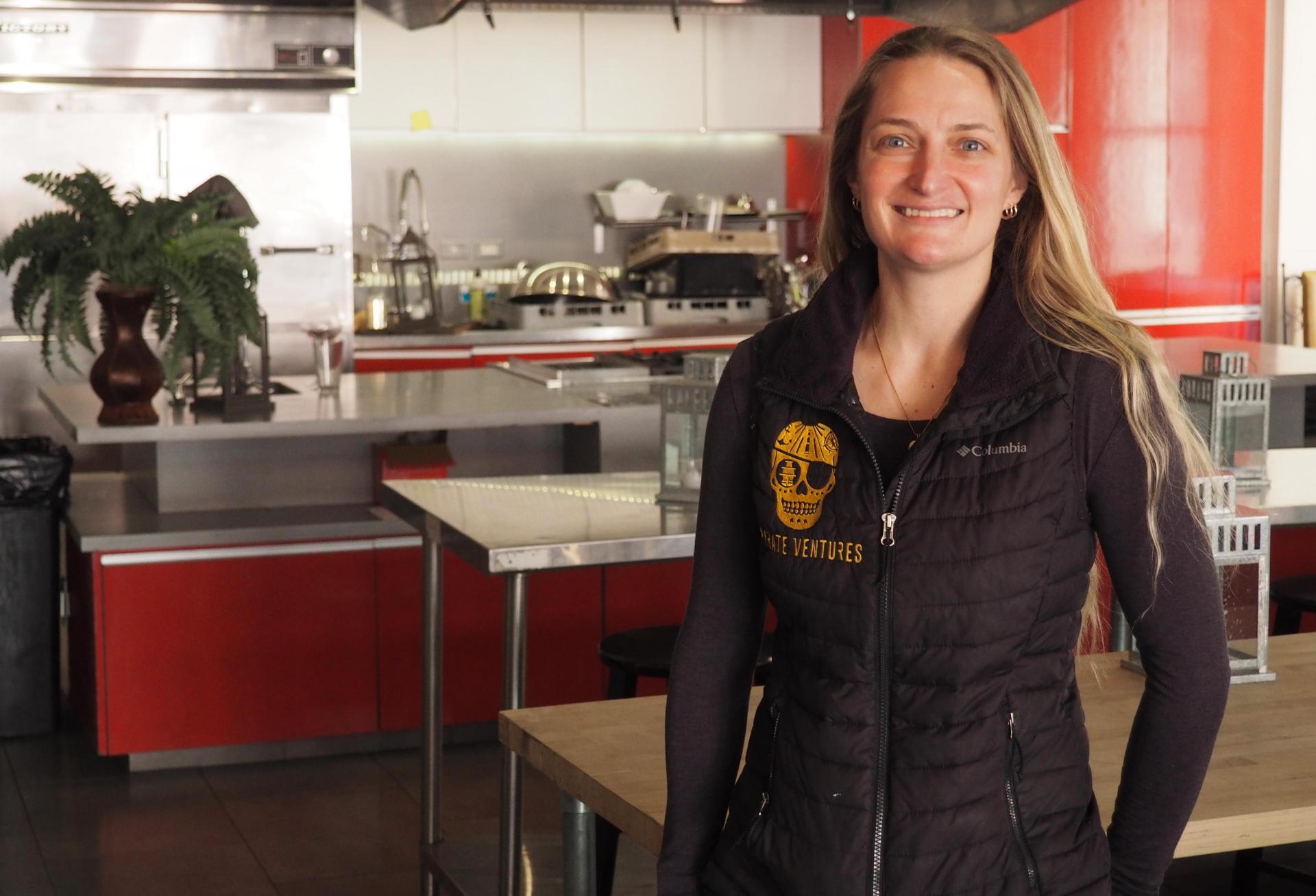 Valero, wearing a vest with an embroidered Pirate Ventures logo, stands in front of a stainless steel professional kitchen
