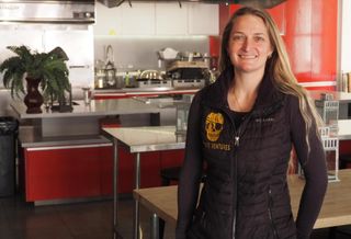 Valero, wearing a vest with an embroidered Pirate Ventures logo, stands in front of a stainless steel professional kitchen