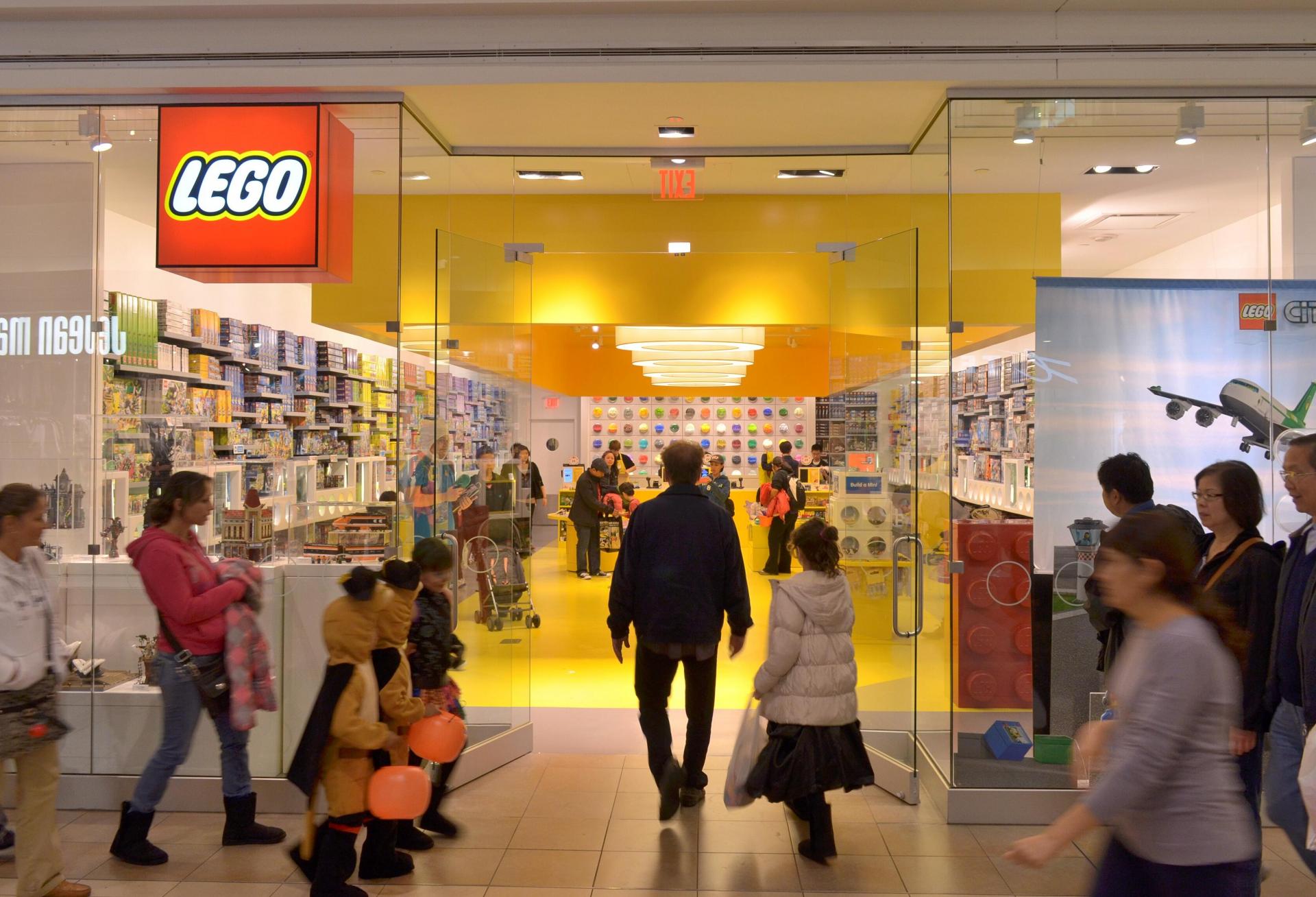 People walk past a Lego Store. 