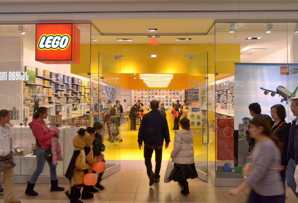 People walk past a Lego Store. 
