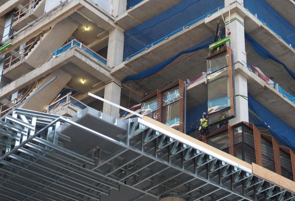 Workers hang a glass panel as part of the façade on the Met Park 7/8 building.