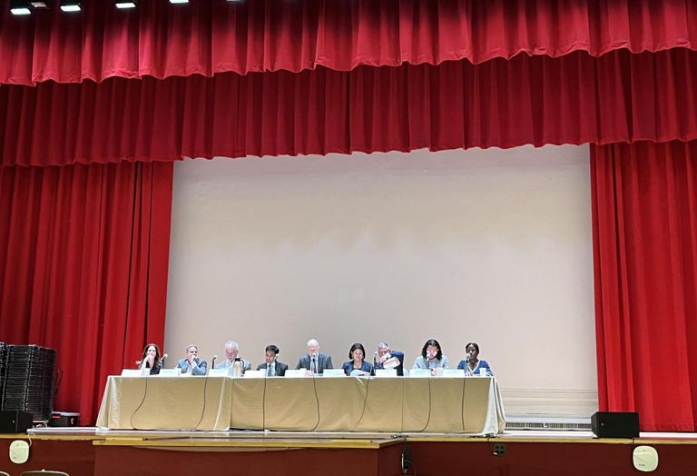 The nine members of the Rent Guidelines Board onstage in an almost-empty theater at Hunter College, while protests continued outside the building.