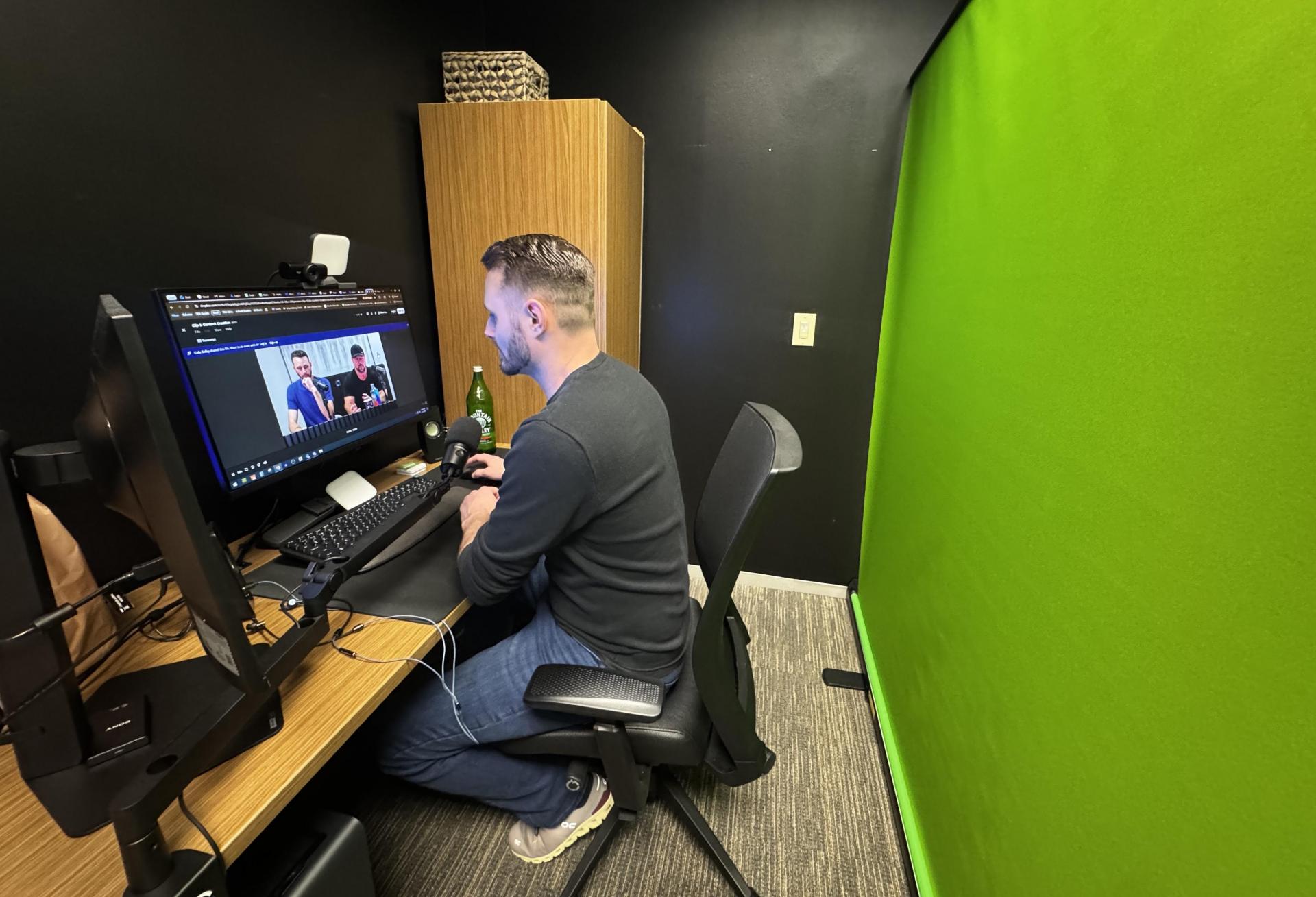 Ian Stapleton editing a video at Track Records. Ian Stapleton is sitting in front of a green screen while video editing.