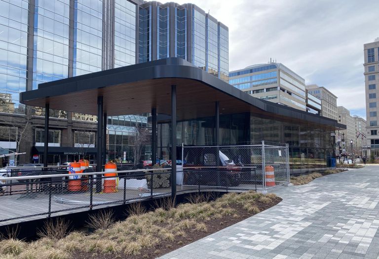 A double-height cafe situated over rain garden fenced off with construction materials on its patio