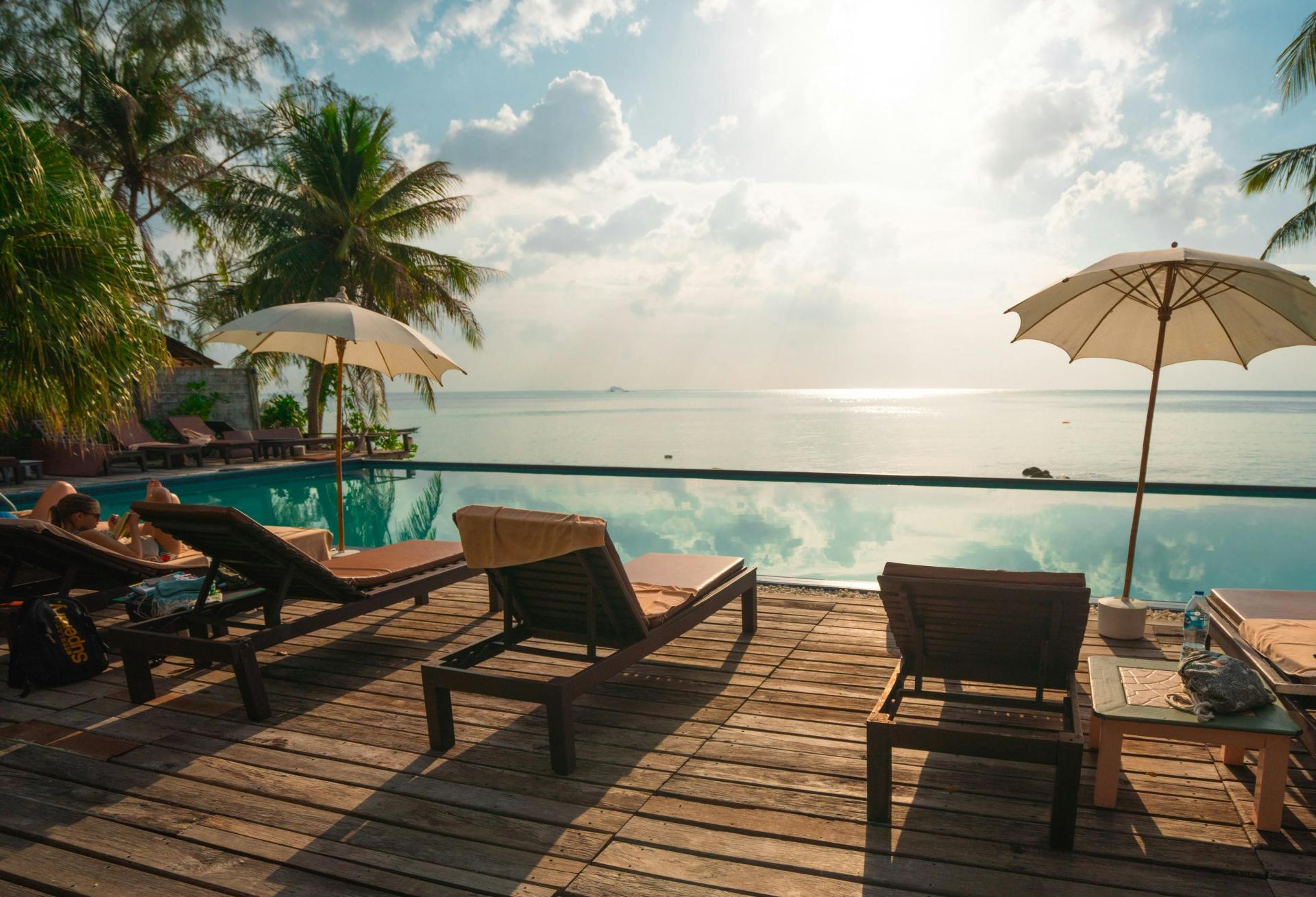 sunchairs in front of a pool at a tropical hotel