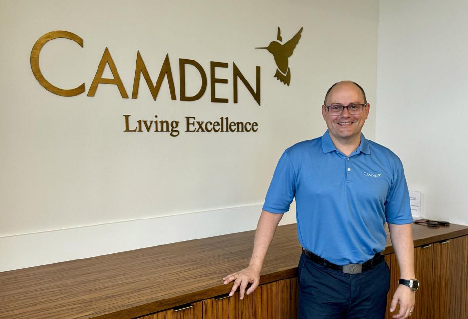 Alex Jessett standing in front of a Camden Realty Trust sign