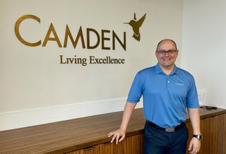 Alex Jessett standing in front of a Camden Realty Trust sign.