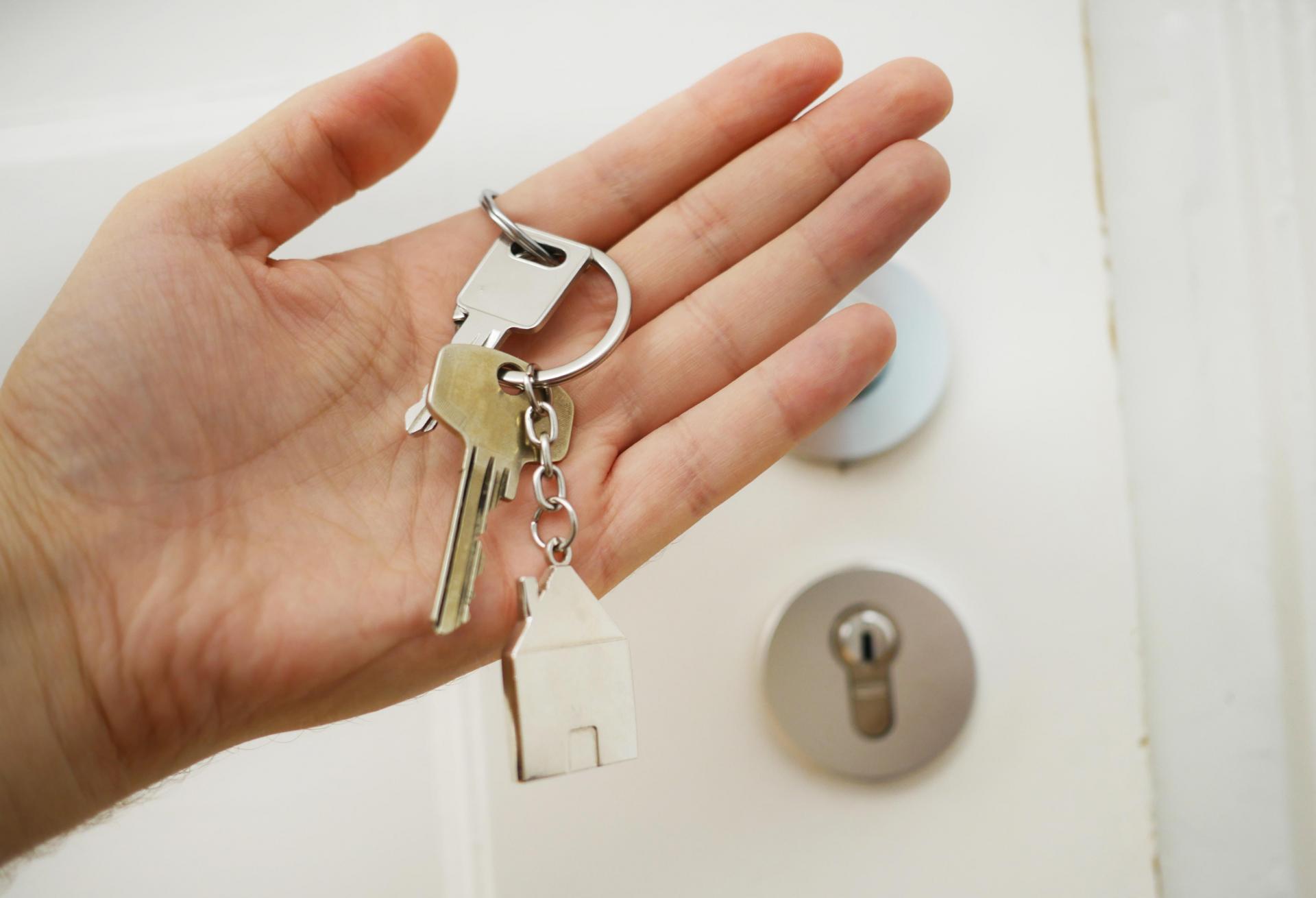 Person holding home keys in front of a door