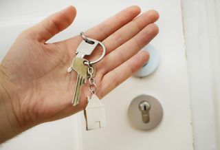Person holding home keys in front of a door