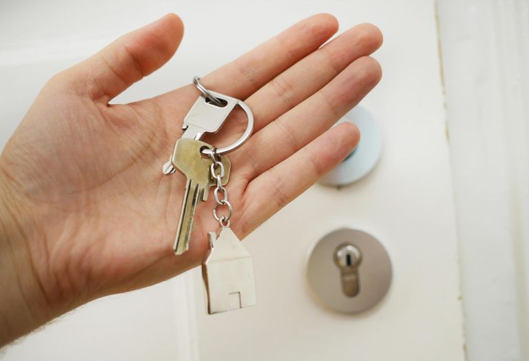 Person holding home keys in front of a door