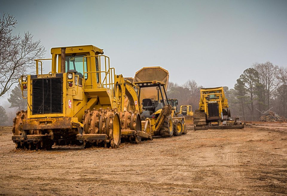 Several construction trucks sitting on ground development.