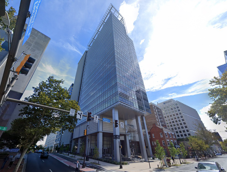 Glass office tower above concrete pillar podium entrance