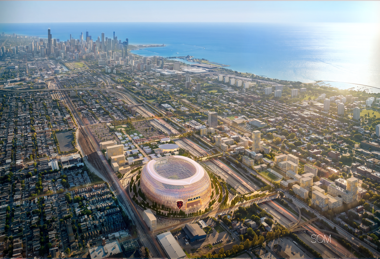 Aerial view of a large stadium labeled "Bears" in an urban area near a lake, with a city skyline and intricate roadways surrounding it.