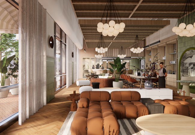 Stylish cafe interior with brown sofas, hanging globe lights, green decor, and large windows. A barista stands behind the counter.