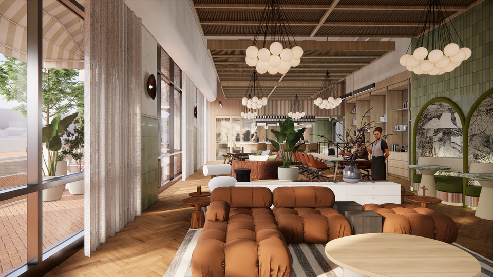 Stylish cafe interior with brown sofas, hanging globe lights, green decor, and large windows. A barista stands behind the counter.