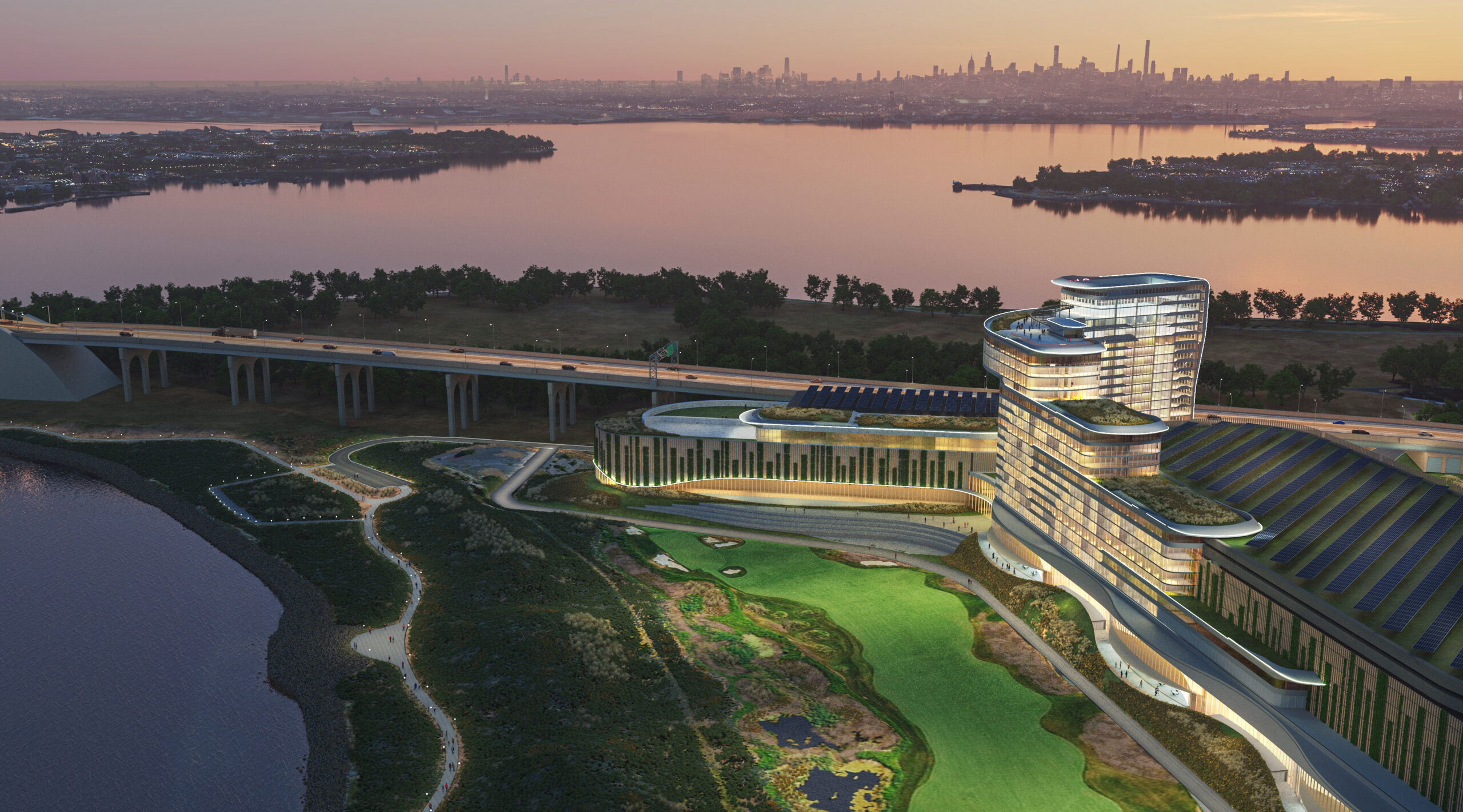 Modern waterfront building with curved architecture, surrounded by greenery and water, at dusk with a city skyline in the background.