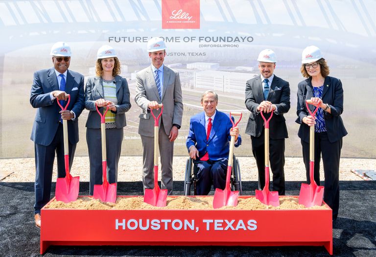 Six people in hard hats participating in a groundbreaking ceremony with shovels, standing in front of a sign reading "Future Home of Foundayo, Houston, Texas."