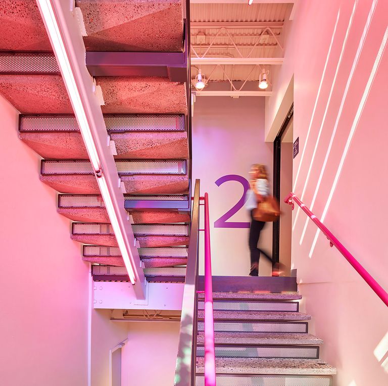 A person walks past pink-lit stairs with a large number 2 on the wall, indicating the second floor.