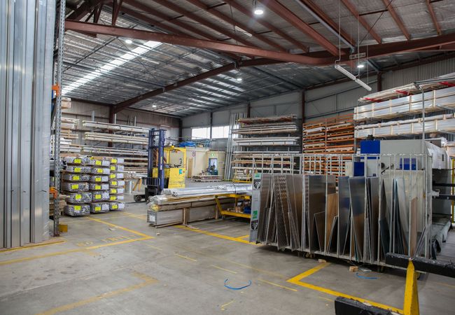 Industrial warehouse with metal shelves, stacked materials, and metal sheets.