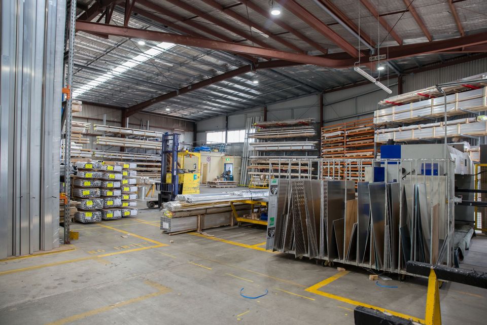 Industrial warehouse with metal shelves, stacked materials, and metal sheets.