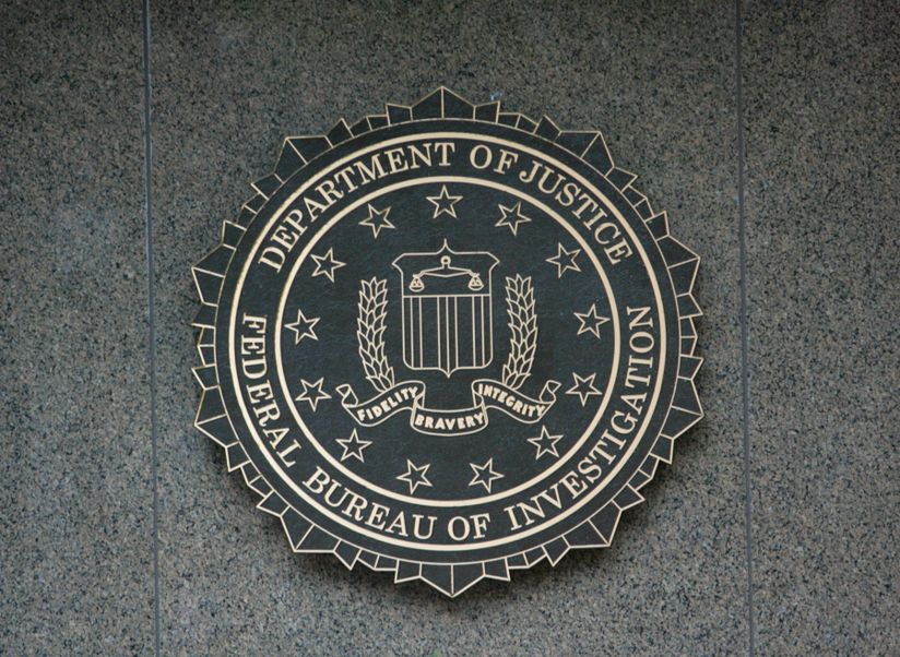 The FBI seal displayed on a gray stone wall, featuring stars, a shield, and an eagle with the words "Fidelity, Bravery, Integrity."