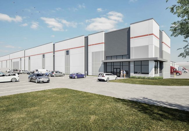 Modern industrial warehouse with a large parking lot, cars, and trucks under a clear blue sky. People are standing near the entrance.