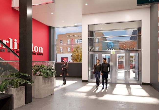 A modern store entrance with a red Burlington sign, potted plants, and a colorful mural. People are entering and exiting through glass doors.
