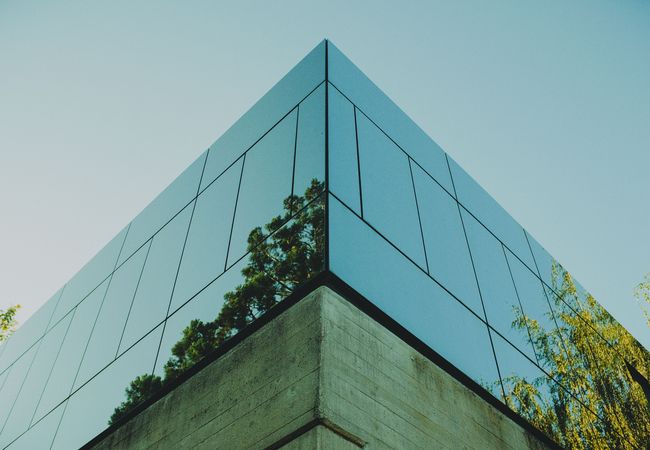 An office building reflecting green trees in the glass