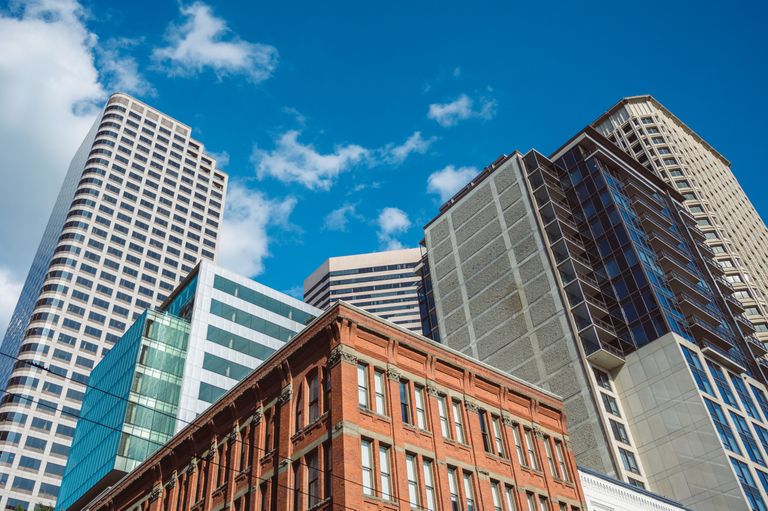 A mix of modern skyscrapers and a historic red brick building under a clear blue sky with scattered clouds.