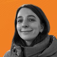 Smiling woman in a jacket against an orange background.
