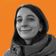 Smiling woman in a jacket against an orange background.