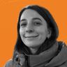 Smiling woman in a jacket against an orange background.