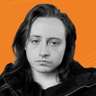 A man with long dark hair and a neutral expression poses in front of an orange background.