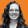A woman with curly hair and glasses smiles against an orange background with subtle wave patterns.