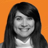 A smiling woman with long hair in a black-and-white portrait set against an orange background with subtle wavy lines.