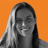 Smiling woman with long hair in a grayscale photo against an orange background with subtle wave patterns.