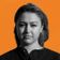 A woman gazes seriously at the camera, set against an orange background with subtle wave patterns.