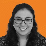A woman with long curly hair and glasses smiles at the camera against an orange background with subtle wave patterns.