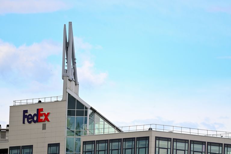 Modern office building with FedEx logo, featuring large windows and distinctive rooftop structures against a blue sky.