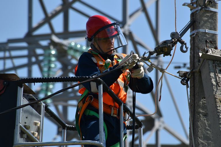 photo of man fixing steel cable