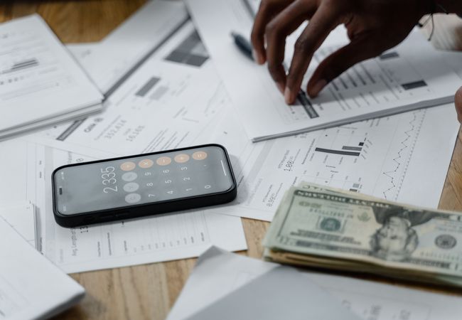 A pile of pills and cash with a phone calculator open