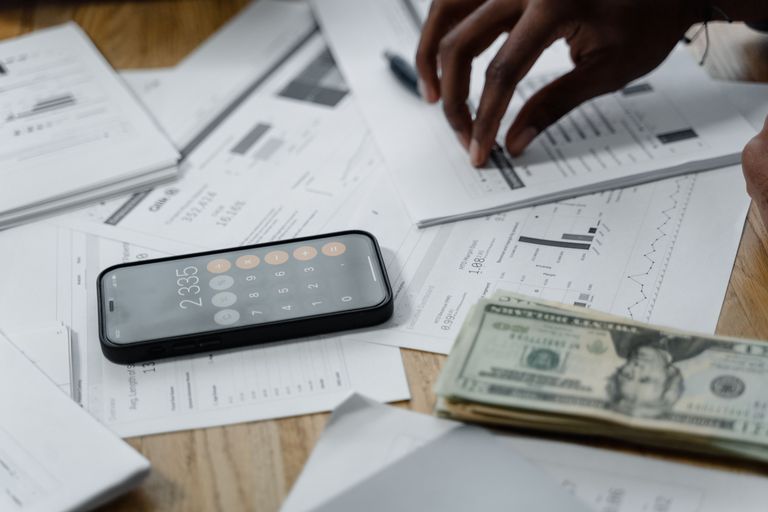 A pile of pills and cash with a phone calculator open