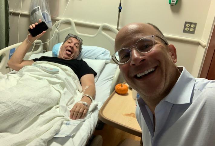 Metropolis Capital Advisors CEO Clifford Mendelson in a hospital bed after Game 7 of the World Series, along with Finmarc's Neil Markus