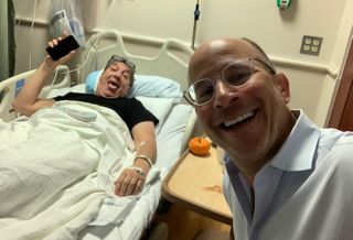 Metropolis Capital Advisors CEO Clifford Mendelson in a hospital bed after Game 7 of the World Series, along with Finmarc's Neil Markus