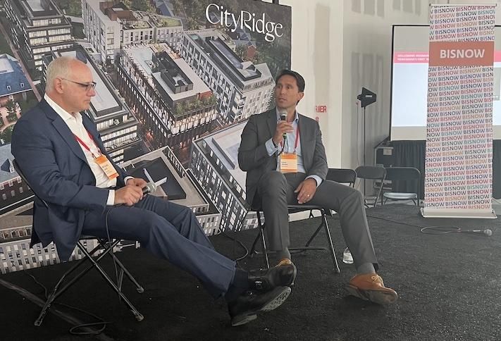 Roadside Development's Richard Lake and Wegmans' Dan Aken speak during a keynote at Bisnow's Northwest D.C. event on June 2, 2022.